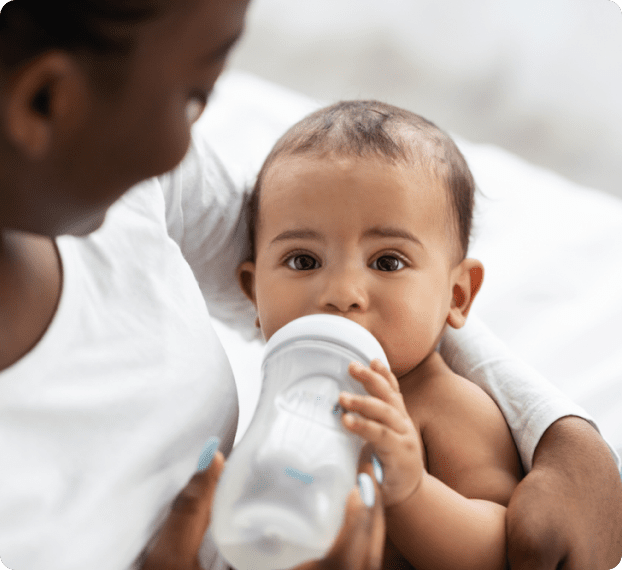 close up of mother giving baby some water using a bottle