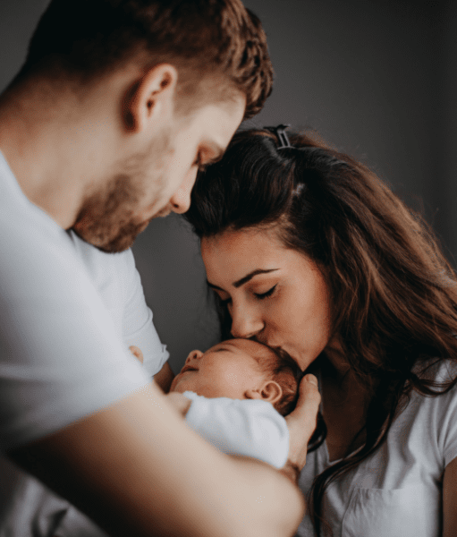 Young family holding and kissing newborn baby in hospital room