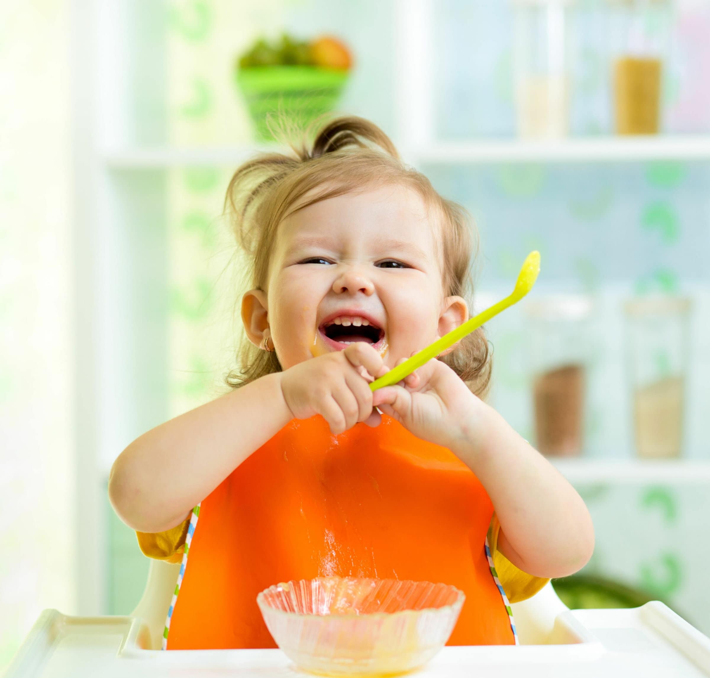 funny baby eating healthy food on kitchen